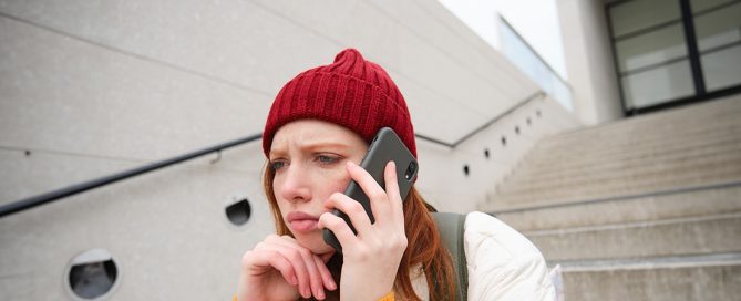 Chica triste esperando respuesta en el móvil, concepto de duelo por ghosting y falta de responsabilidad afectiva en relaciones.