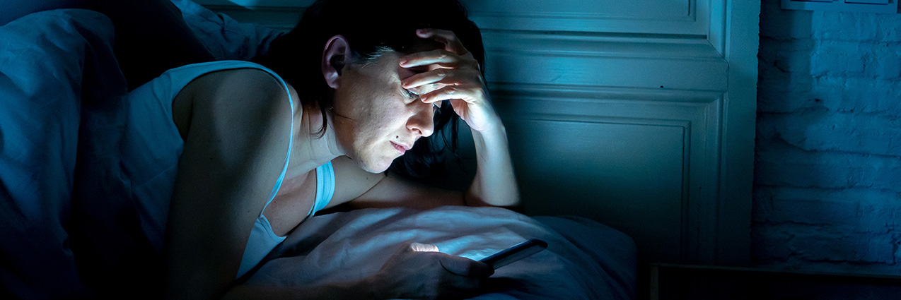 psicologo-online-celos-pareja-sale-sin-mi-apego-ansioso.jpg Persona tumbada mirando el móvil con expresión ansiosa mientras su pareja está fuera, representando los celos y la ansiedad de separación en pareja.
