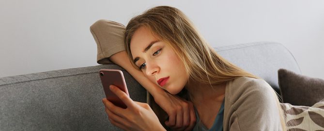 Persona mirando el móvil con expresión decaída, representando el efecto de compararse constantemente con los demás en redes sociales