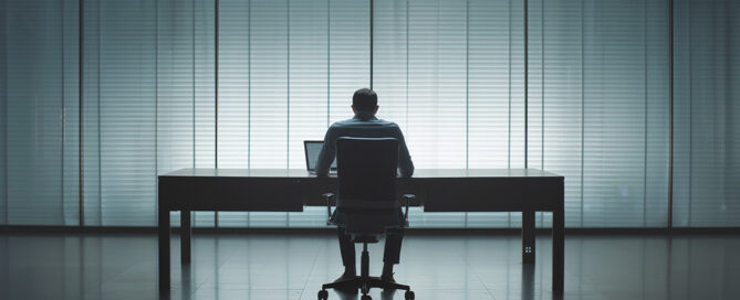 Persona sentada sola en una oficina vacía, representando la duda de quien sufre acoso laboral y no sabe si lo está imaginando