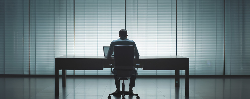 Persona sentada sola en una oficina vacía, representando la duda de quien sufre acoso laboral y no sabe si lo está imaginando